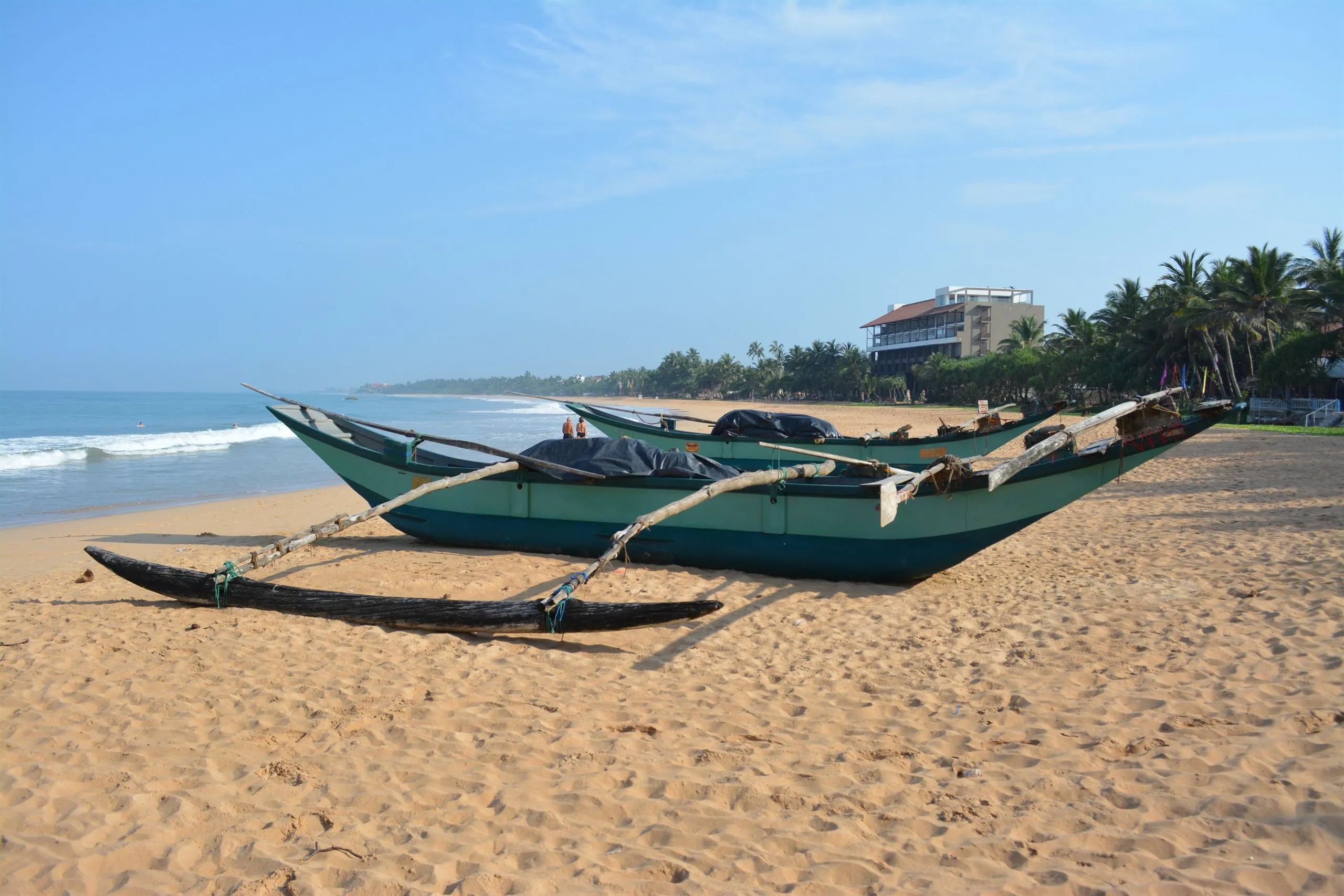 Two green fishing boats pulled up on the beach at Bentota