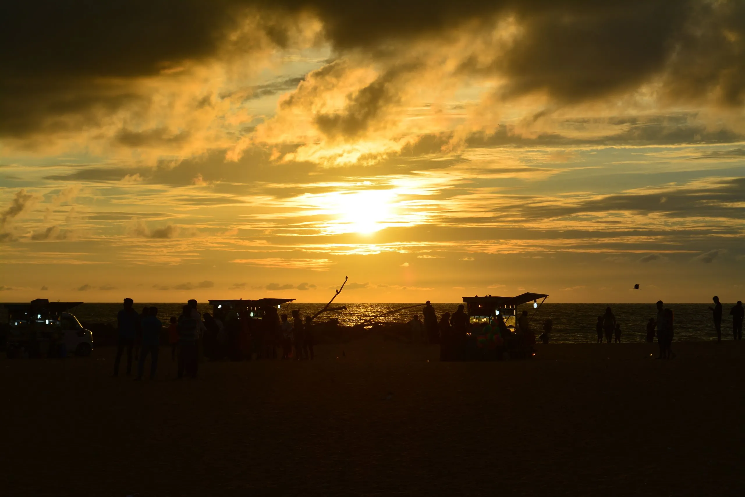 Negombo beach at sunset, boats and stalls in silhouette