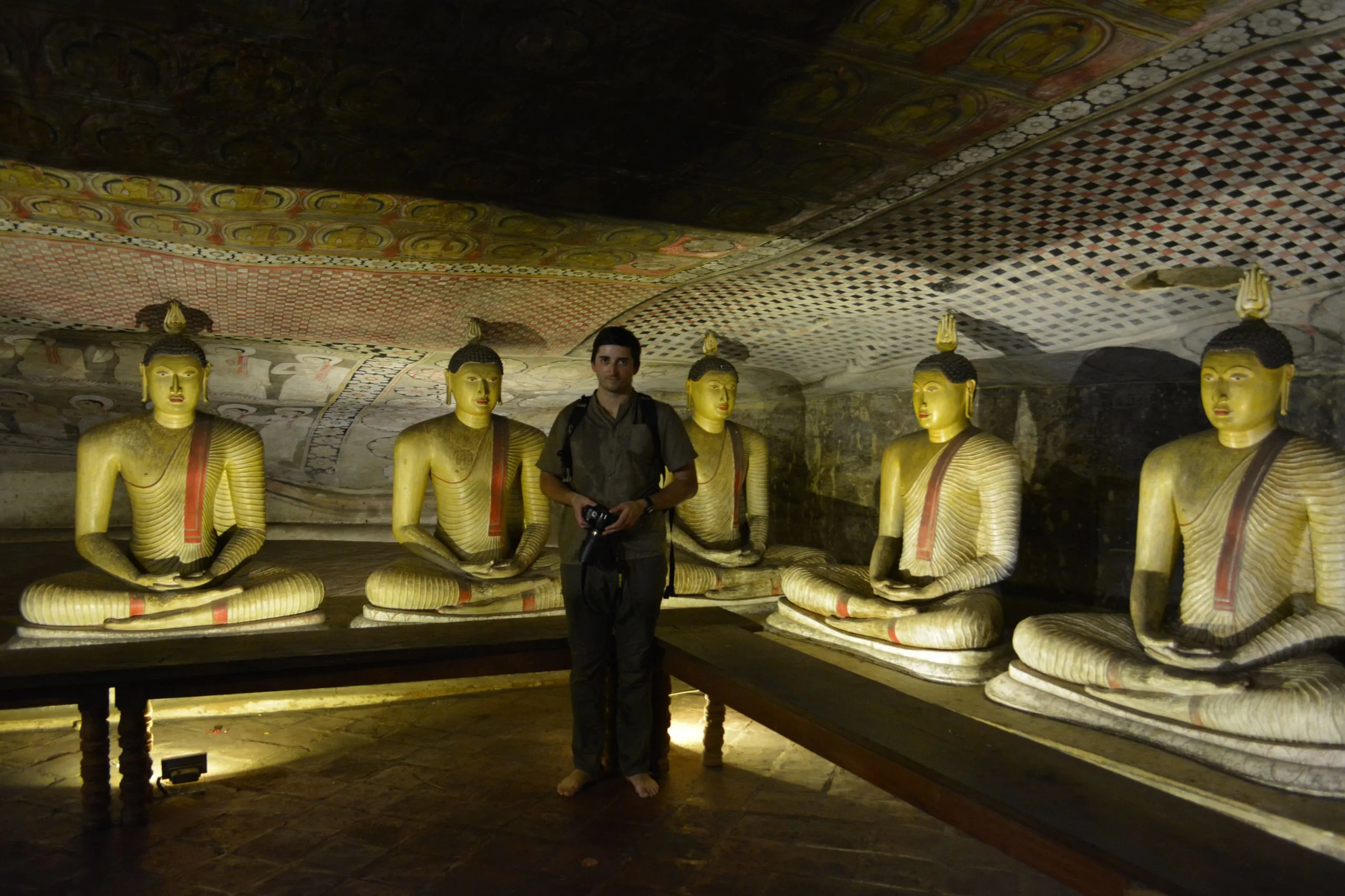 Buddha statues and a painted ceiling inside a rock cave temple